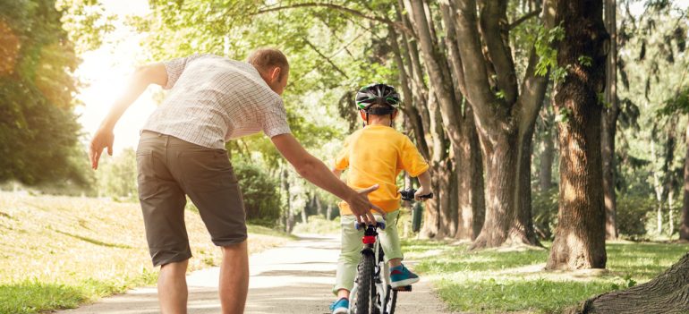 A father teaching his young son to ride a bike.