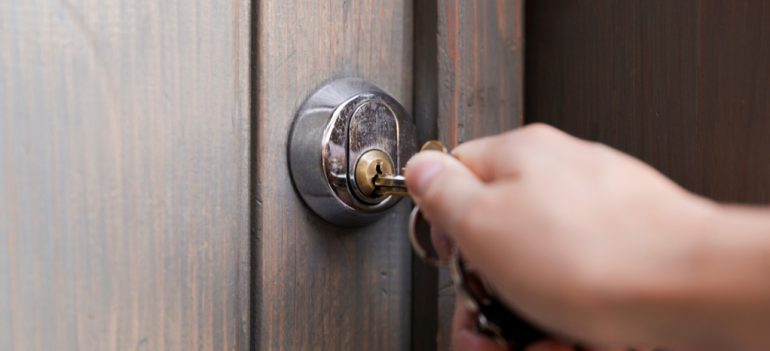 A hand unlocking a front door.
